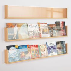 three wooden bookshelves holding several different types of books on each shelf, and one is hanging from the wall