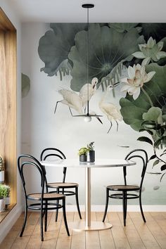 a dining room table with chairs and a mural on the wall behind it that has birds flying over water lilies