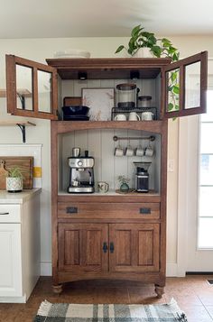 a wooden cabinet with pots and pans on it in a kitchen next to a rug