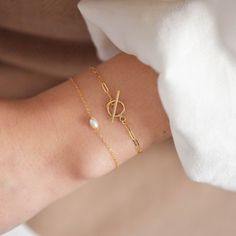 "This bracelet features a small toggle closure on a dainty paperclip gold chain that measure 2 mm wide and can be made to fit your wrist snugly. Toggle measures 9mm wide. Be sure to measure your wrist if you are going for a tight fit like the model who is wearing the 5.75 inches. Otherwise, the standard length at department stores for women's bracelets is 7 inches. This item is 14k gold filled and is tarnish-resistant, water-resistant, and hypoallergenic. --------------------♥ PROMOS ♥---------- Classic Oval Link Bracelets As Gift, Timeless Adjustable Chain Bracelet With Oyster Detail, Timeless Adjustable Oyster Chain Bracelet, Gold Charm Bracelet Gift With Clasp, Bracelets With Spring Ring Clasp As Gift, Adjustable Link Sterling Silver Bracelet Gift, Adjustable Sterling Silver Link Bracelet Gift, Modern Adjustable Bracelets With Clasp, Modern Adjustable Bracelet With Clasp