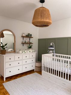 a baby's room with a crib, dresser and mirror on the wall