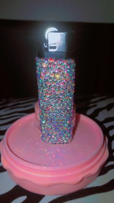 a cell phone is sitting on top of a pink stand with some colorful beads in it