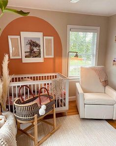 a baby's room with an orange wall and white furniture