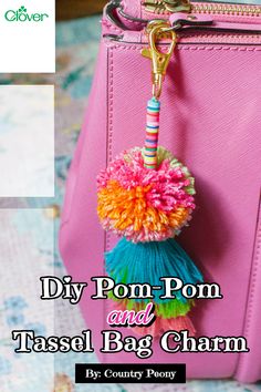 a pink purse with pom - pom and tassel bag charm on it