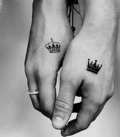 two people holding hands with tattoos on their arms and one is wearing a crown tattoo