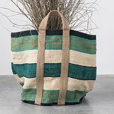 a woven bag sitting on top of a table next to a potted grass plant