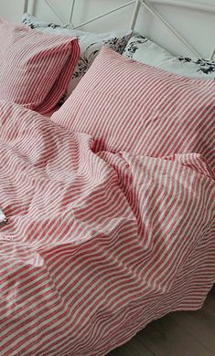 an unmade bed with red and white striped sheets