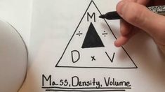 a hand holding a pen over a piece of paper with the word m s density volume written on it