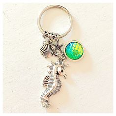 a keychain with a sea horse and shell charm on it's side