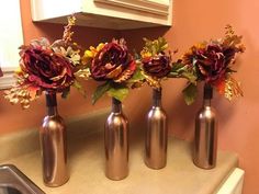 three vases with flowers in them sitting on a counter top next to a sink