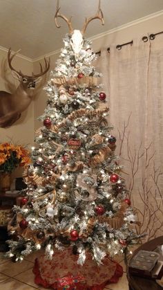 a decorated christmas tree with deer heads on the top and antlers hanging from the ceiling