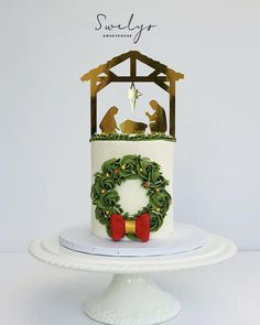 a white cake with a nativity scene on top and a wreath in the middle