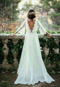 the back of a woman's wedding dress with long sleeves and an open neckline