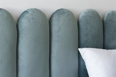 an upholstered headboard and pillow against a white wall with vertical horizontals