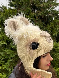 a woman wearing a knitted hat with a fuzzy animal on it's side