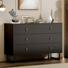 a black and gold dresser in a living room with pictures on the wall behind it