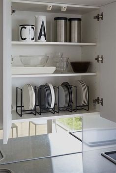 plates and cups are sitting on shelves in the kitchen