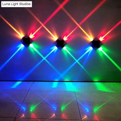 four lights that are on the wall in front of a tiled floor and one is brightly colored