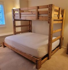 a wooden bunk bed sitting in a bedroom next to a wall mounted lamp and window