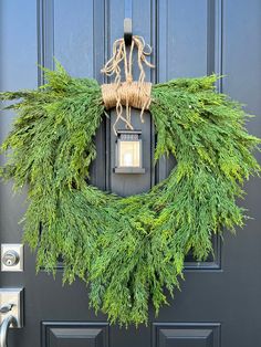 a wreath is hanging on the front door with a light and some branches around it