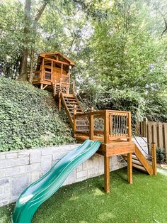 a wooden slide next to a brick wall and green grass in front of a house