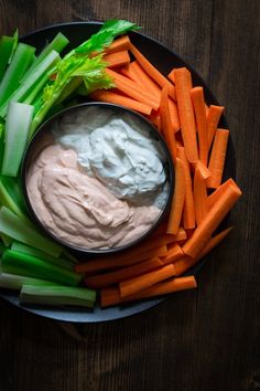 carrots, celery, and dip in a bowl on a black plate