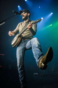 a man with a guitar on stage in front of some microphones and green lights