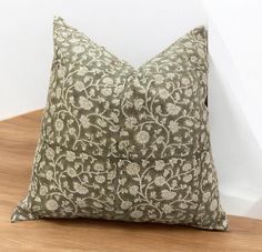 a green and white pillow sitting on top of a wooden floor next to a wall