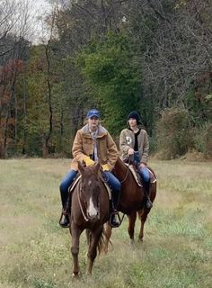 two people are riding horses through the grass