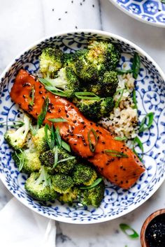 a bowl filled with broccoli and salmon next to another bowl full of rice