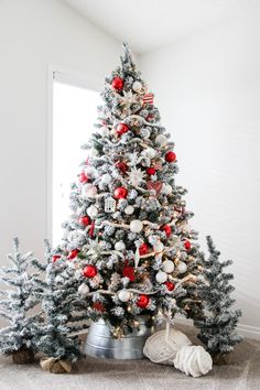 a decorated christmas tree with red and white ornaments in a tin can on the floor