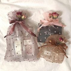 three different types of perfumes in bags on a white sheeted surface with ribbons and bows