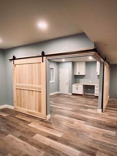 an empty room with wood flooring and sliding barn doors in it's center