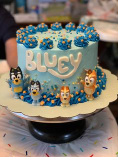 a birthday cake with blue frosting and cartoon characters on the top is sitting on a table