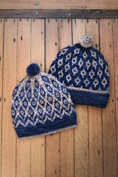 two knitted hats sitting on top of a wooden floor