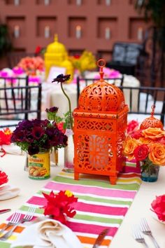 the table is set with colorful flowers and place settings