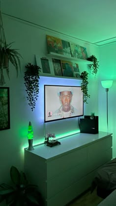 there is a television that is on in the room with green lights and plants around it