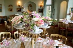 there is a table set with flowers and teacups on the tables in this room