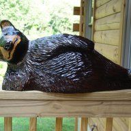 a statue of a bear laying on top of a wooden porch next to a window