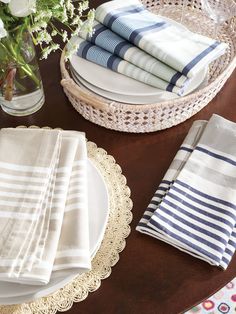 the table is set with white and blue striped napkins, plates, and flowers