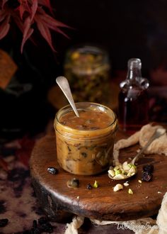 a jar filled with food sitting on top of a wooden table next to a spoon