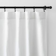 a white curtain hanging on the side of a wall next to a black rod handle