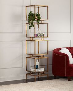 a red chair sitting in front of a white wall next to a shelf filled with plants