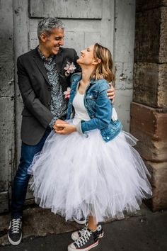 a man standing next to a woman in a tutu skirt and jacket on the street