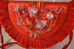 Beautifully beaded and embellished Shibori Ribbon accents this red evening bag with shades of red, tangerine and hot pink! Its covered with Swarovski crystals in various sizes and shapes, and its embellished on the shoulder strap with more sparkling beads! Hand beaded by myself and Mary McCoy in our Las Vegas studios, this striking evening bag measures approximately 8 inches across, about 5 1/2 inches tall, and about 2 inches wide, just big enough to tuck in your cell phone, mad money, and a lip Luxury Red Embellished Bag, Luxury Embellished Red Bags, Red Embellished Bag For Formal Occasions, Elegant Red Embellished Evening Bag, Formal Red Embellished Bag, Red Embellished Clutch For Formal Occasions, Glamorous Red Embellished Bag, Red Embellished Evening Bag For Festive Occasions, Luxury Red Beaded Bag