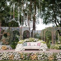 an outdoor seating area with flowers and greenery on the ground, surrounded by archways