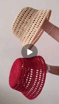 a hand holding a red and white crocheted hat