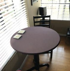 a round table with two chairs in front of it and a window behind the chair