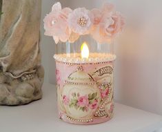 a candle that is sitting on a shelf next to a vase with flowers in it