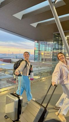 two people walking with luggage at an airport